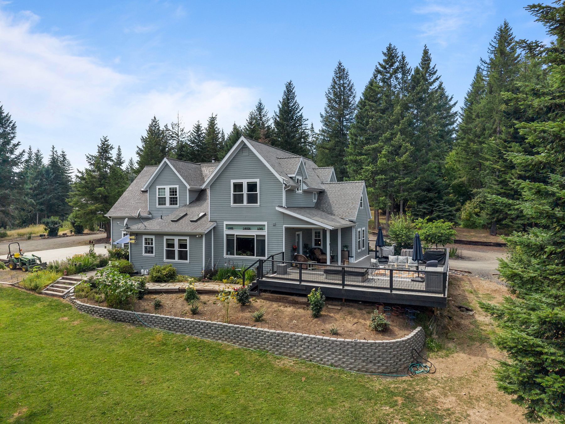 Grey farmhouse exterior with wraparound deck in the pines