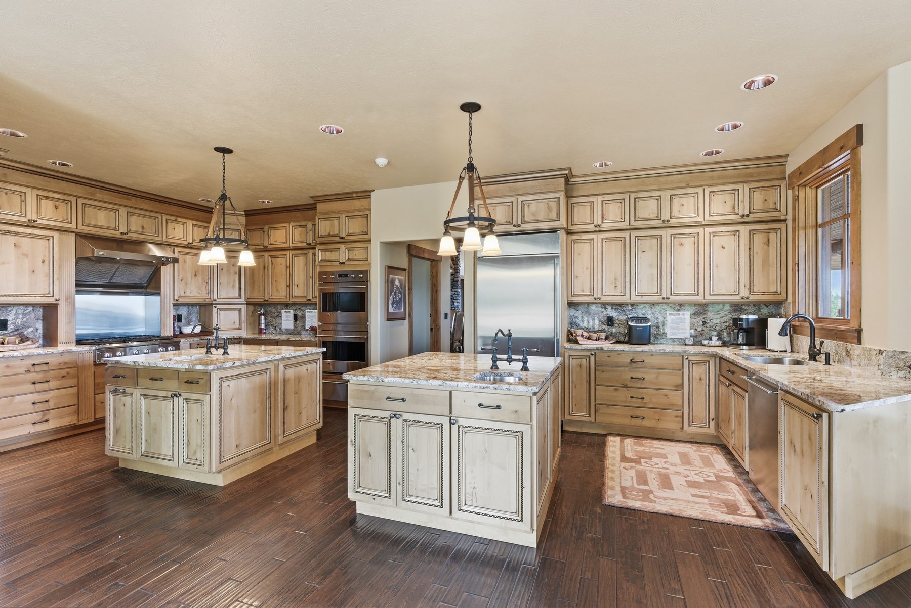 Double-island kitchen with light cabinetry and hardwood floors