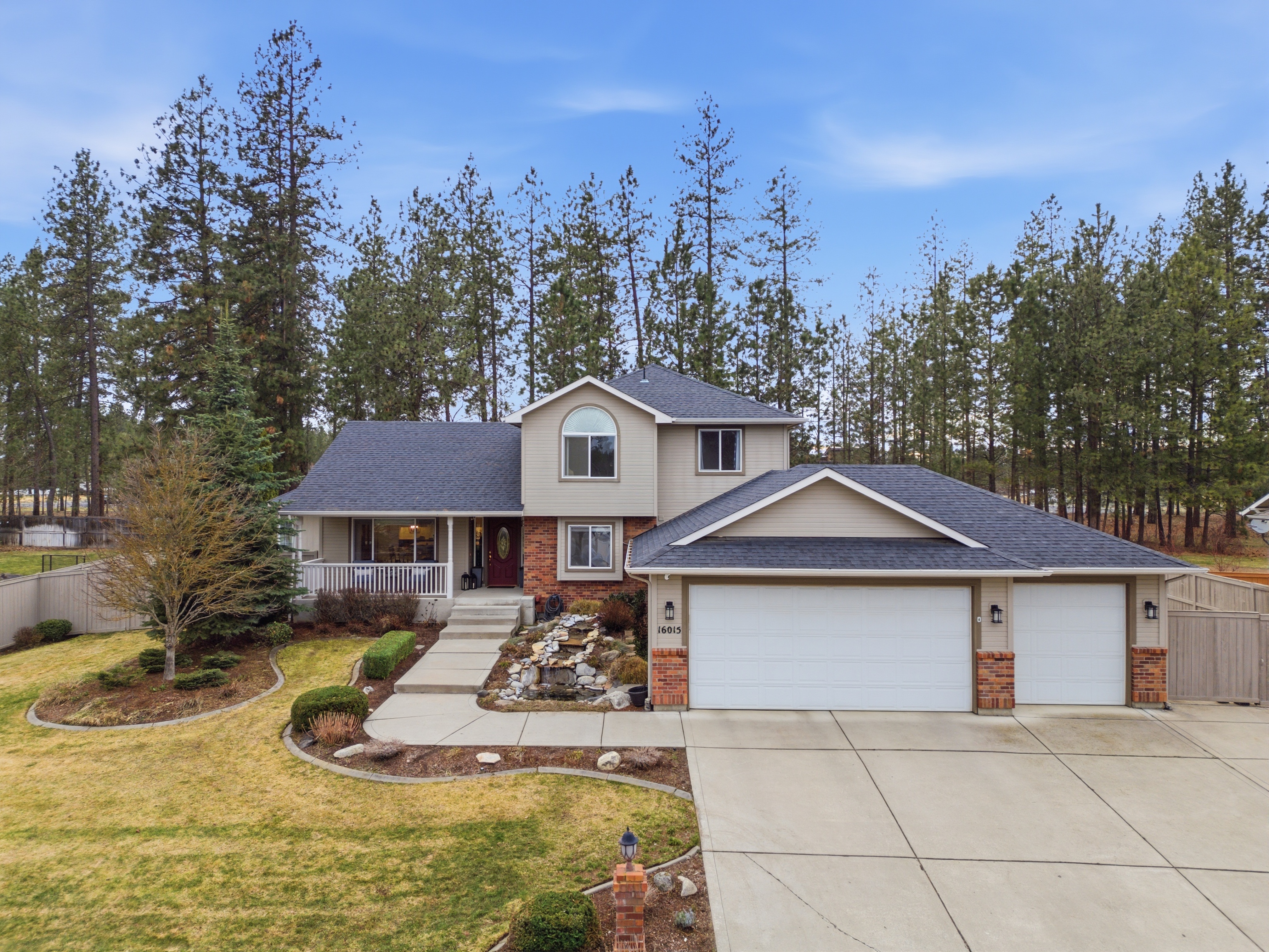 Two-story home with brick accents and pine backdrop